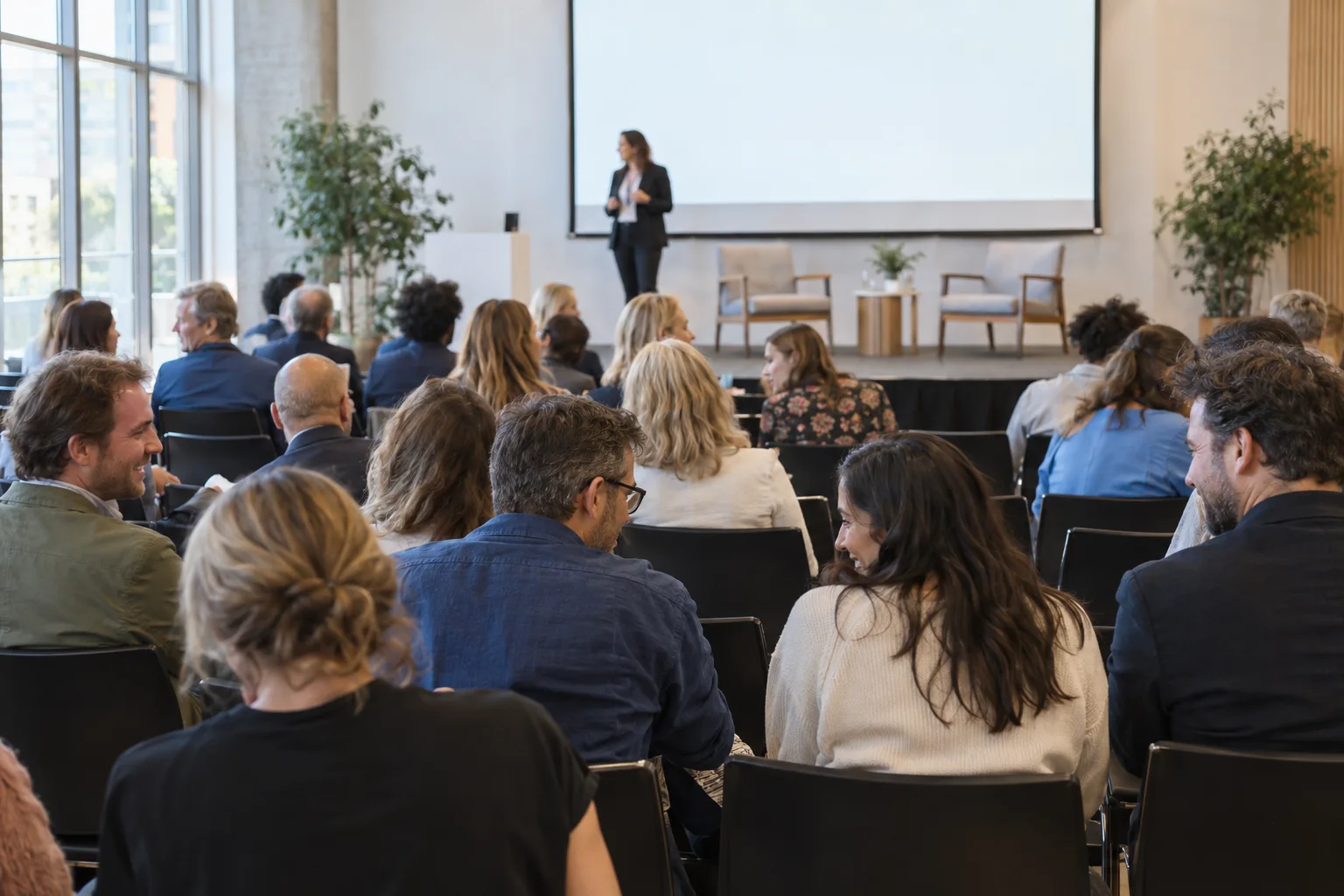 People gathered in a conference hall with a speaker on stage