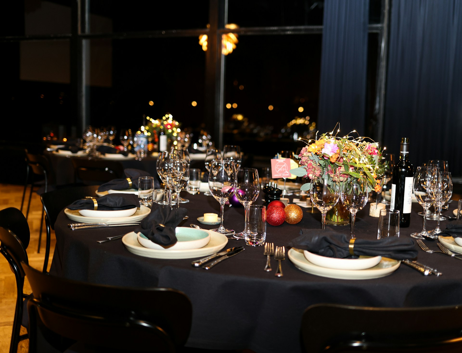 A long réveillon table set with oysters and champagne flutes under low light, a bûche de Noël waiting on the sideboard and a printed menu at each place